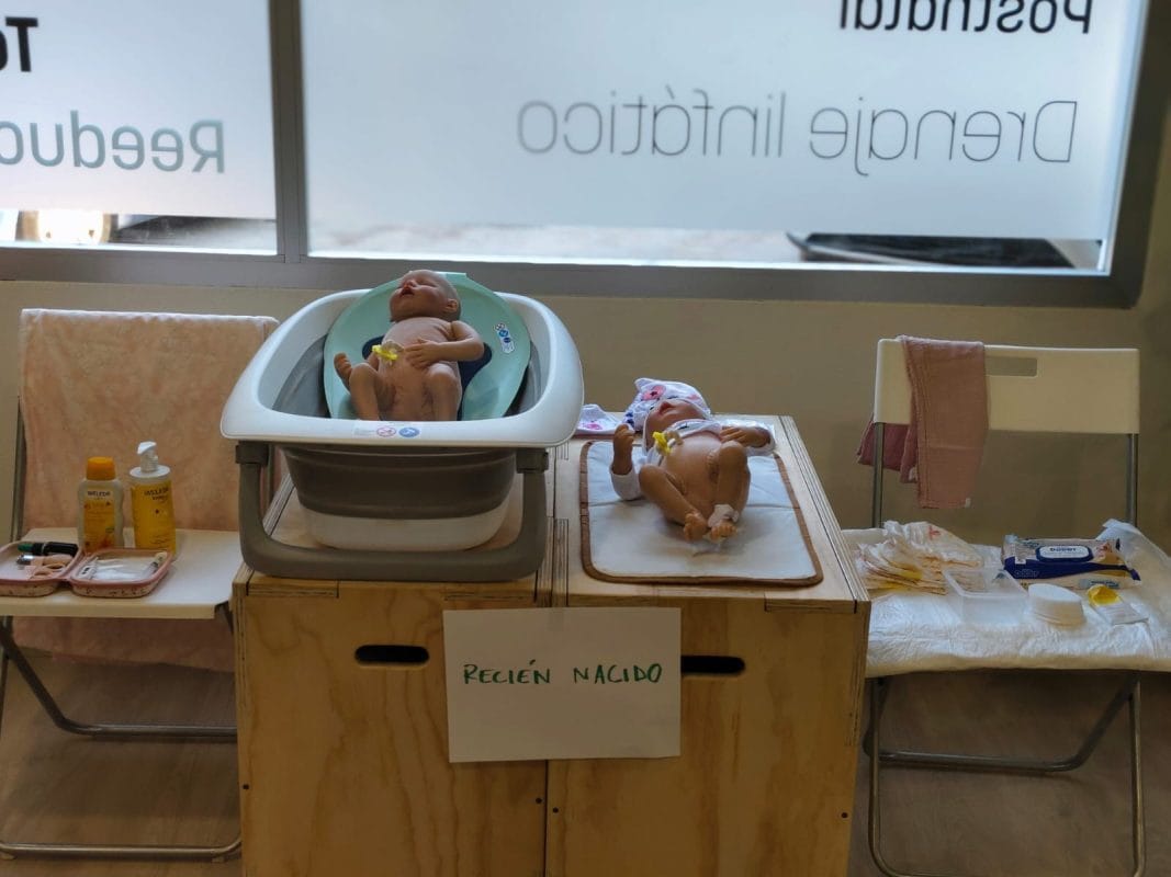 Preparación al parto presencial en Valencia Muñecos de bebé en bañera y cambiador durante el taller de preparación al parto sobre cuidados del recién nacido